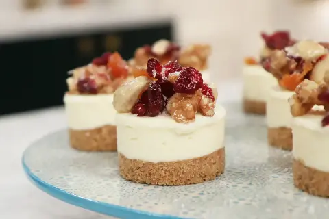 Små mini cheesecakes med nötter och torkad frukt på en blåmönstrad tårtfat.