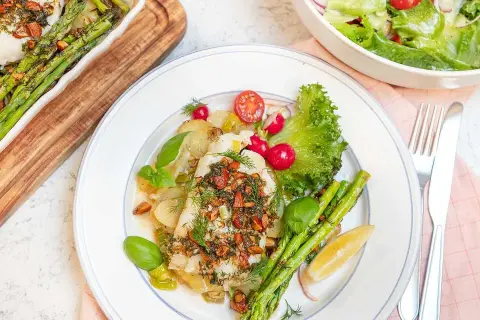 En portion torsk med citronsås, serverad med sparris, potatis och en fräsch sallad.