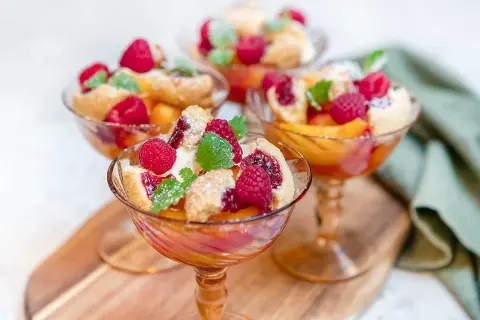 Tre eleganta glas med persika, hallon och smuldeg. En klassisk peach melba som ser ljuvlig ut.