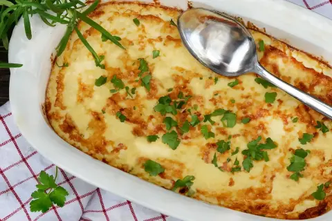 En gyllene omelett i ugn, toppad med färsk persilja och en sked redo att servera. Perfekt för en mysig frukost eller lätt lunch.