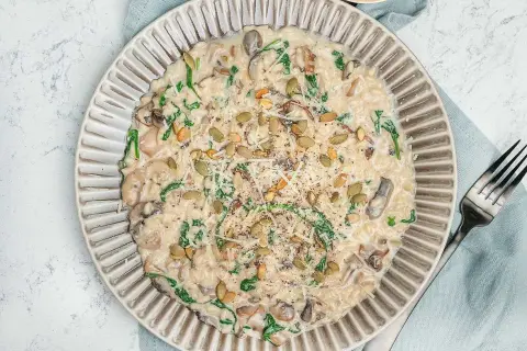 Krämig risotto svamp med spenat och pumpafrön, toppad med parmesan och svartpeppar. En härlig rätt som värmer själen.