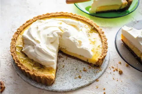 En krämig key lime pie med fluffig grädde, en bit serverad på en grön tallrik.