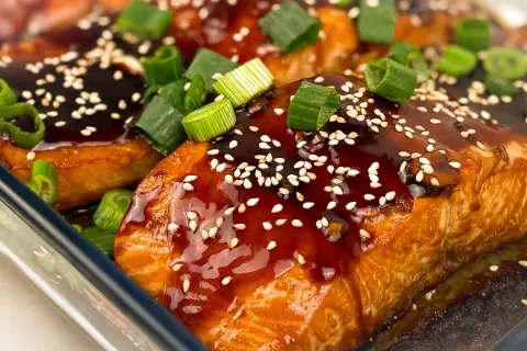 Saftig teriyaki lax med sesamfrön och färsk grön lök, redo att avnjutas.