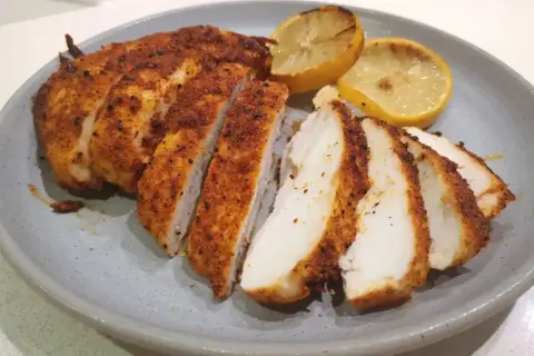 Saftig kyckling i airfryer, skivad och serverad med grillade citronklyftor. Perfekt för en snabb och god middag.
