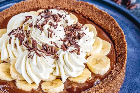 En krämig banoffee paj med vispgrädde, bananskivor och chokladströssel. En dröm för alla sötsugna!