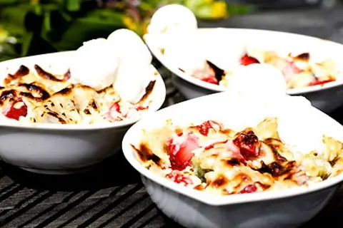 Tre skålar med jordgubbs-smulpaj toppad med vaniljglass. Ett perfekt Gino recept för en sommardessert.