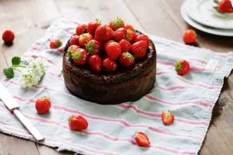 En kladdkaka med nutella, toppad med färska jordgubbar, ligger på en randig duk.