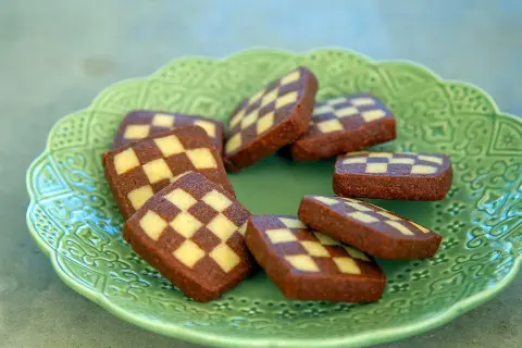 Schackrutor recept: Mörka och ljusa kakor i rutmönster på en grön, mönstrad tallrik. Perfekt för fikat!