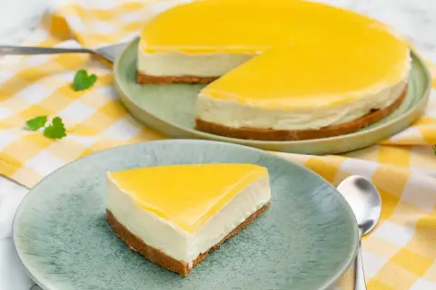 En krämig citron cheesecake med gul topping, en bit serverad på en tallrik.