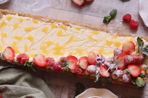 En avlång cheesecake med passionsfrukt, toppad med färska jordgubbar, hallon och mynta.