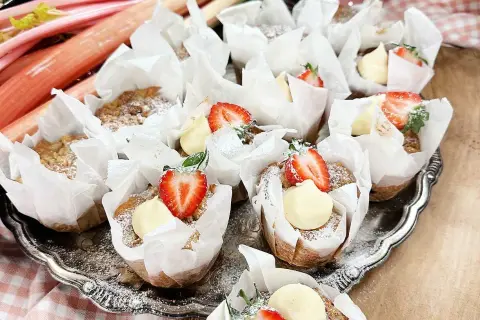 En bricka med rabarber muffins, toppade med grädde och jordgubbar. Perfekt för fikat!
