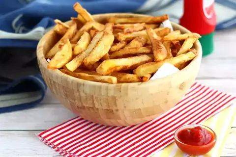 En skål med gyllene, krispiga egna pommes frites, redo att doppas i ketchup.