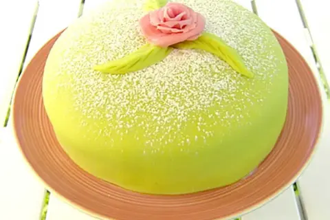 Grön prinsesstårta med rosa marsipanros och blad, pudrad med florsocker. Perfekt för ett prinsesstårta recept.