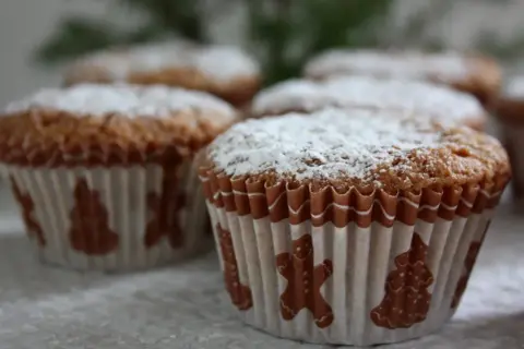 Pepparkaksmuffins recept: Nybakade muffins med pepparkakssmak, pudrade med florsocker och dekorerade med pepparkaksfigurer.