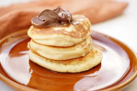 En stapel fluffiga amerikanska pannkakor med chokladkräm på toppen. Perfekt för ett amerikanskt pannkakor recept!