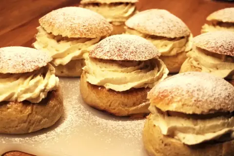 Flera gammaldags semlor med rikligt med grädde och pudrat florsocker. En klassisk svensk fika.