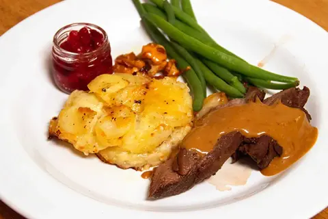 Hjortstek i ugn med potatisgratäng, lingonsylt och gröna bönor. En klassisk svensk måltid.