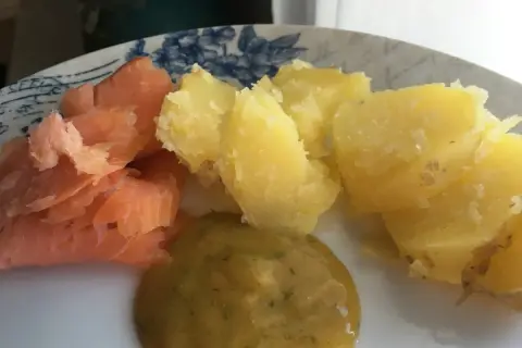En tallrik med gravad lax, kokt potatis och en klick gravlaxsås. Perfekt för ett snabbt och gott recept.