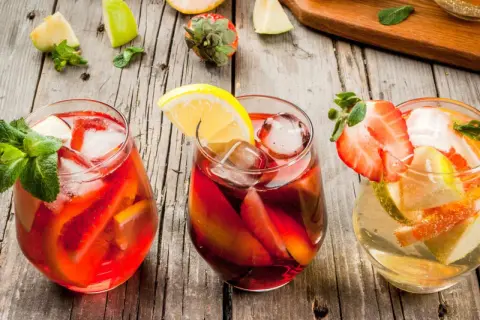 Tre glas med färgglad sangria, fyllda med frukt och is. Perfekt för ett somrigt recept sangria.