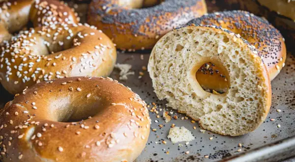 Färska bagels med sesamfrön och vallmofrön, perfekta för ditt bagels recept. En skuren bagel visar det fluffiga inre.