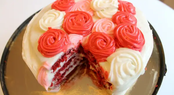 En skivad red velvet cake med fluffig frosting i rosformar.