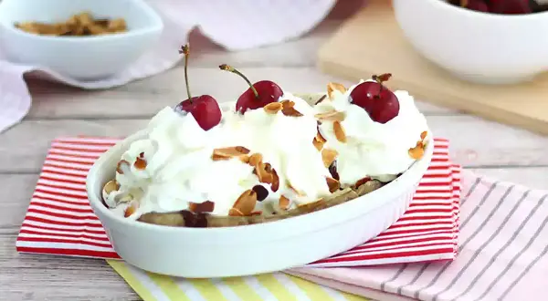 En läcker banana split med vispgrädde, körsbär och mandelflagor. En klassisk dessert som alltid går hem.