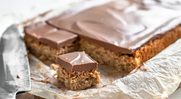 En bit av en långpanne kaka med nougat. Kakan har en krispig botten och toppas med ett lager choklad.