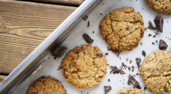 Nybakade havrekakor med chokladbitar på en plåt. Perfekt för ett enkelt havrekakor recept.