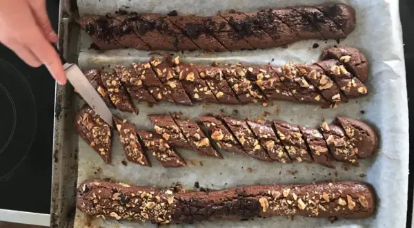 Chokladsnittar recept: Nybakade chokladkakor med nötter skärs upp på en plåt.