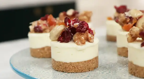 Små mini cheesecakes med nötter och torkad frukt på en blåmönstrad tårtfat.