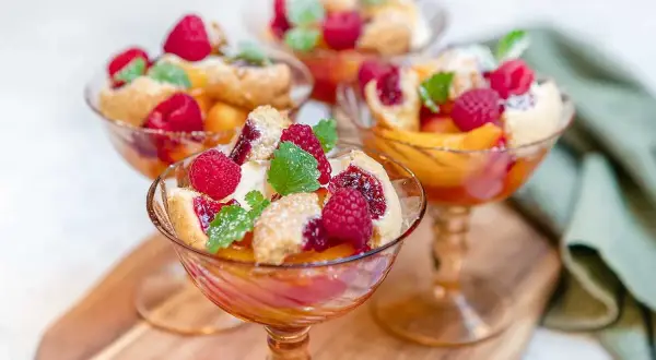 Tre eleganta glas med persika, hallon och smuldeg. En klassisk peach melba som ser ljuvlig ut.