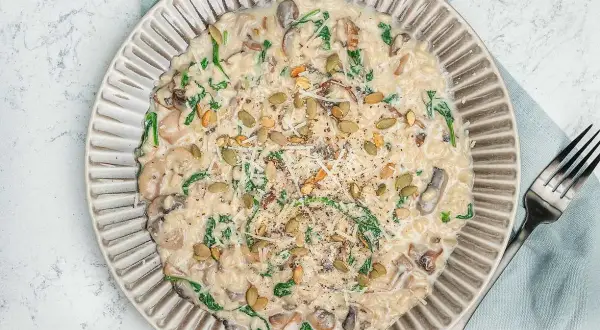 Krämig risotto svamp med spenat och pumpafrön, toppad med parmesan och svartpeppar. En härlig rätt som värmer själen.