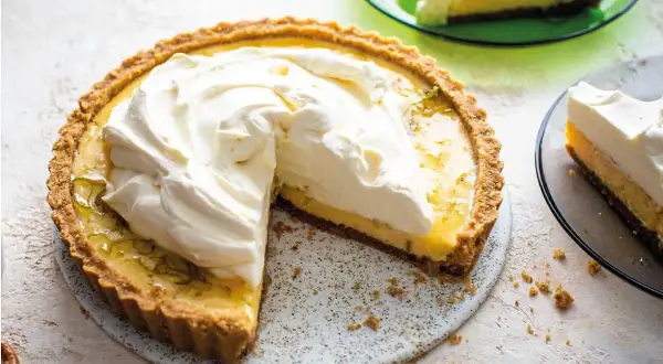 En krämig key lime pie med fluffig grädde, en bit serverad på en grön tallrik.