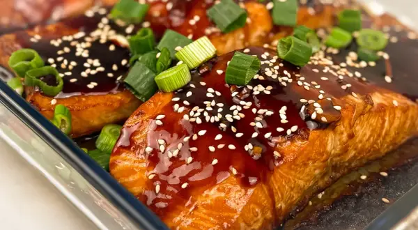 Saftig teriyaki lax med sesamfrön och färsk grön lök, redo att avnjutas.