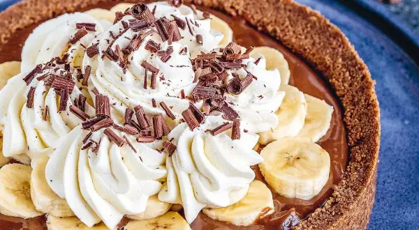 En krämig banoffee paj med vispgrädde, bananskivor och chokladströssel. En dröm för alla sötsugna!