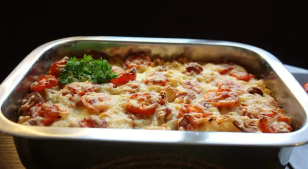 En gyllene makaronipudding med tomater och ost, redo att serveras. Ett perfekt recept för en mysig middag.