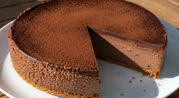 Chokladig oreo cheesecake med ett lager kakao på toppen, en bit är bortskuren.
