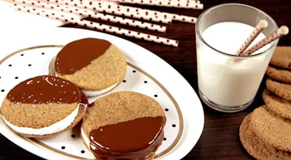 S'mores i ugn: tre chokladöverdragna kex med marshmallowfyllning på en prickig tallrik, bredvid ett glas mjölk och fler kex.