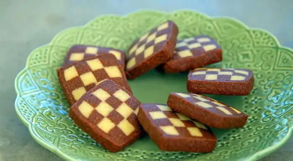 Schackrutor recept: Mörka och ljusa kakor i rutmönster på en grön, mönstrad tallrik. Perfekt för fikat!