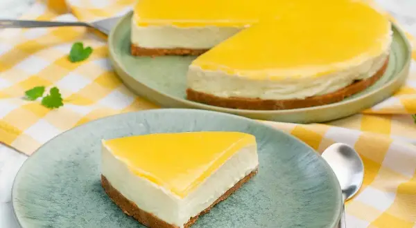 En krämig citron cheesecake med gul topping, en bit serverad på en tallrik.