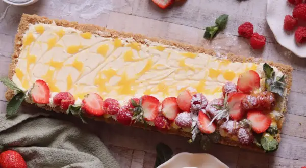 En avlång cheesecake med passionsfrukt, toppad med färska jordgubbar, hallon och mynta.