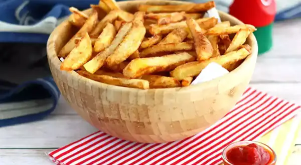 En skål med gyllene, krispiga egna pommes frites, redo att doppas i ketchup.