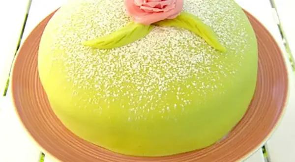 Grön prinsesstårta med rosa marsipanros och blad, pudrad med florsocker. Perfekt för ett prinsesstårta recept.