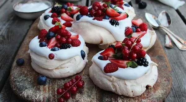 Små pavlova med grädde och färska bär som jordgubbar, hallon, blåbär och vinbär. En härlig sommardessert.