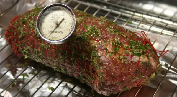 En fransyska i ugn, förberedd för låg temperaturstekning med örtkryddor och en köttermometer.