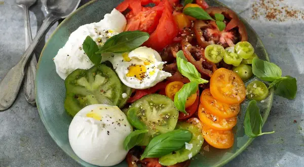 En krämig burrata med en blandning av färgglada tomater och färsk basilika. Ett enkelt och gott burrata recept.