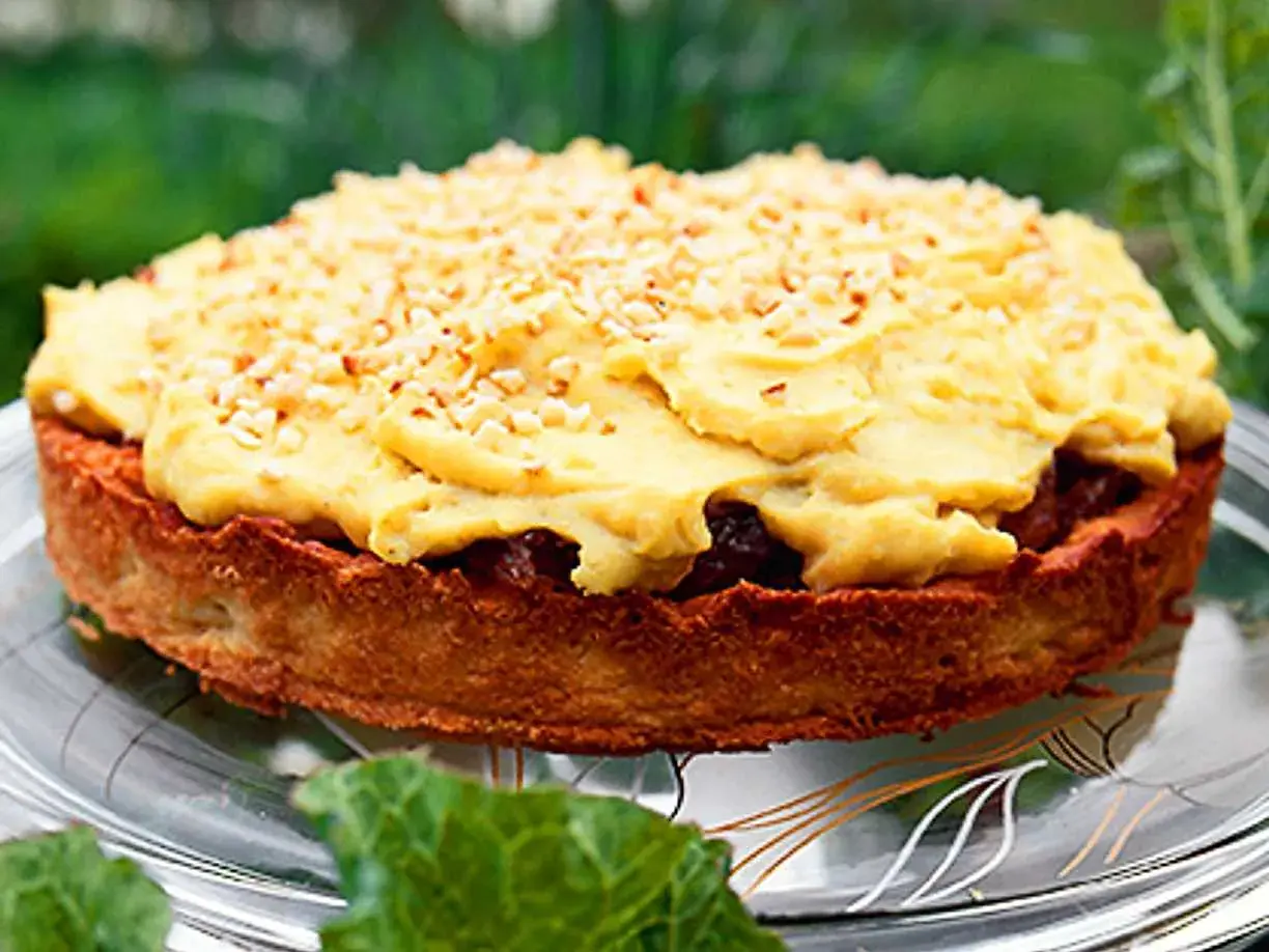 En härlig rabarberkompott tårta med gul kräm och nötter, serverad på ett fat utomhus.