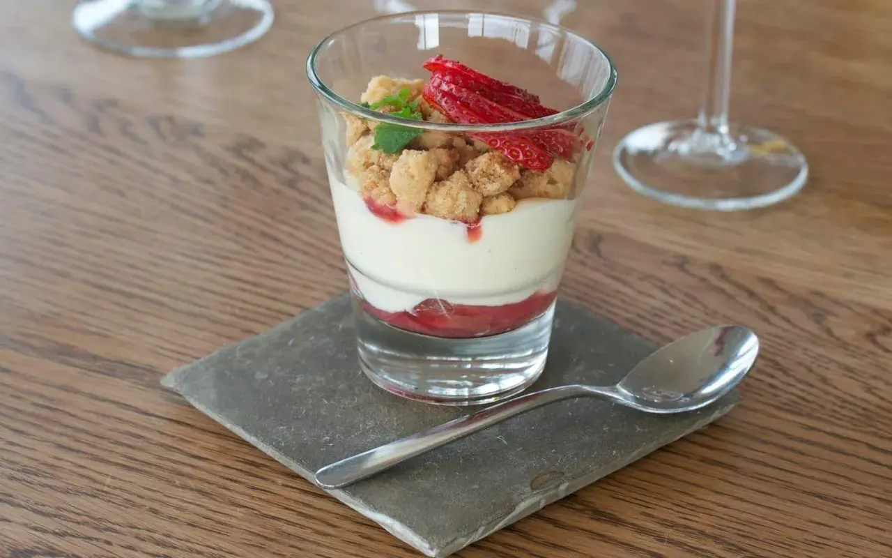 En läcker rabarberdessert i glas med krämig vaniljkräm, smuldeg och färska jordgubbar. Perfekt för en somrig fika.