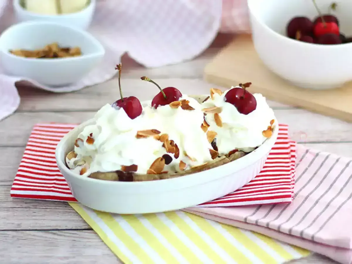 En läcker banana split med vispgrädde, körsbär och mandelflagor. En klassisk dessert som alltid går hem.