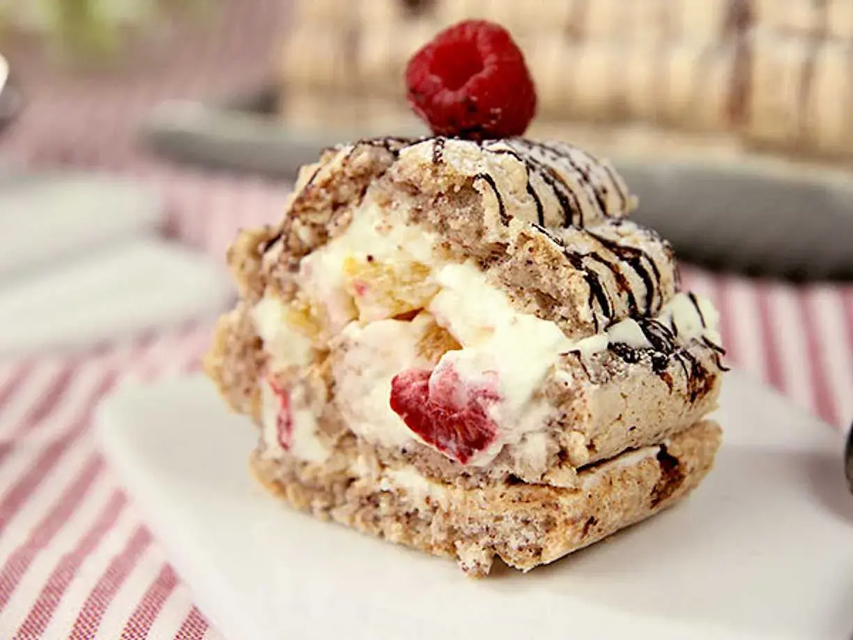 En läcker budapestbakelse med grädde och frukt, toppad med en hallon och chokladdrizzle.